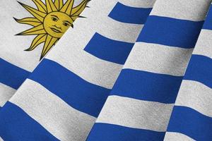 Uruguay flag with big folds waving close up under the studio light indoors. The official symbols and colors in banner photo