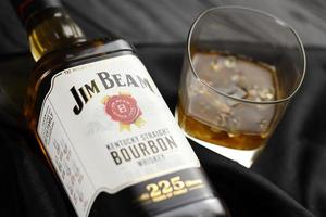 KYIV, UKRAINE - MAY 4, 2022 Jim Beam original alcohol bottle on wooden table with black fabric photo