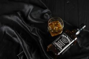 KYIV, UKRAINE - MAY 4, 2022 Jack Daniels original alcohol bottle on wooden table with black fabric photo