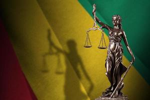 Guinea flag with statue of lady justice and judicial scales in dark room. Concept of judgement and punishment photo