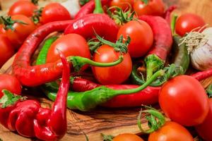 Selective focus on hot capsicum and tomatoes on a wooden board, close-up, fresh produce from a farmer's market. Food ingredients of mediterranean diet and healthy eating. photo