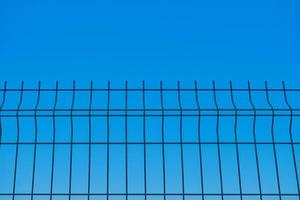Metal fence against the background of a blue boundless sky, a blurred background, the idea of freedom and the removal of restrictions, a background for a poster or postcard photo