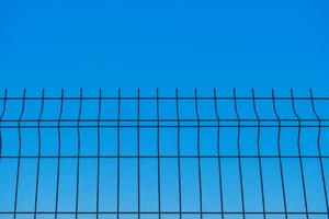 Metal fence against the background of a blue boundless sky, a blurred background, the idea of freedom and the removal of restrictions, a background for a poster or postcard photo