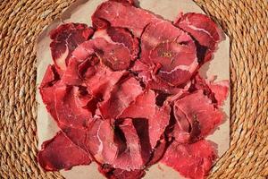 Turkish bacon, pastrami or kayseri pastirma. Fresh sliced pastrami on a paper lining, top view. photo