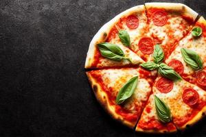 Italian pizza Margherita with tomato sauce Mozzarella cheese basil on a dark concrete background. Pizza recipe and menu. photo