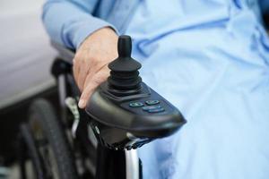 Asian elderly woman disability patient sitting on electric wheelchair in park, medical concept. photo