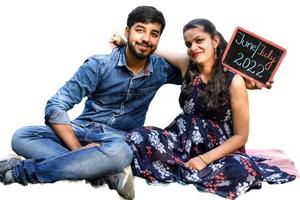 Indian couple posing for maternity baby shoot with white plain background. The couple is posing in a lawn with green grass and the woman is falunting her baby bump in Lodhi Garden in New Delhi, India photo