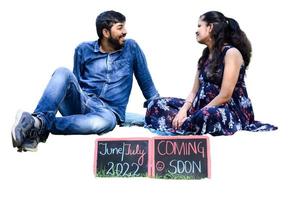 Indian couple posing for maternity baby shoot with white plain background. The couple is posing in a lawn with green grass and the woman is falunting her baby bump in Lodhi Garden in New Delhi, India photo