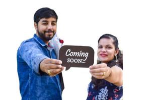 Indian couple posing for maternity baby shoot with white plain background. The couple is posing in a lawn with green grass and the woman is falunting her baby bump in Lodhi Garden in New Delhi, India photo
