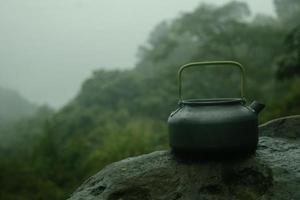 té maceta en parte superior de Roca en el montaña con niebla antecedentes foto