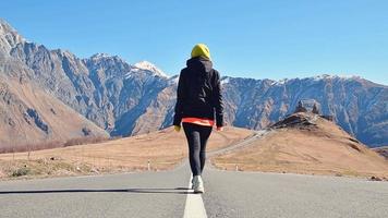 toerist wandelen Gaan naar Gergeti drie-eenheid kerk in Georgië. beroemd Gergeti drie-eenheid tsminda sameba kerk . mooi Georgisch landschap in val, herfst vroeg winter video