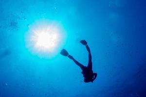 divers under boat for deco time in the blue photo