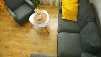 Cozy apartment living room with sofa and yellow pillows and stylish table, window with bright day light outside in winter video