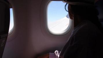 Jordânia, 2022 - mulher parece Fora a janela do a vôo avião asas Visão com bruxo logotipo. jovem passageiros estão viajando de avião, assistindo a céu a partir de acima video