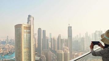 Dubai, Émirats arabes unis, 2022 - moderne touristique femelle voyageur prendre photo à la recherche à burj khalifa la tour contre brumeux blanc ciel, Dubai, Émirats arabes unis video