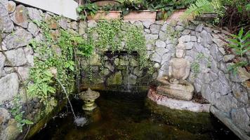 Buddha statue beside the water fountain with waterfall video