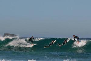 un grupo de cuatro surfistas saltando y montando en grande olas foto