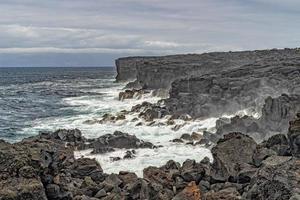 mar en tempestad rompiendo olas en acantilado de roca de lava foto