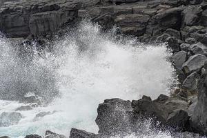 sea in tempest breaking waves on lava rock cliff photo