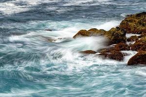 sea in tempest breaking waves on lava rock cliff photo