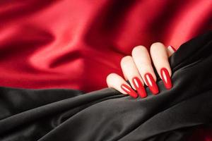 Hands of a young girl with red  and black manicure on nails photo