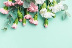 A bouquet of white and pink carnations with eucalyptus branches on a soft green background. photo