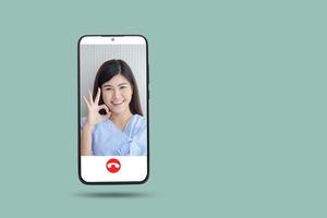 Black smartphone concept Connect to communication via online technology. The doctor can examine the patient via video call. Light green background. Clipping Path. Female patient thumbs up ok photo