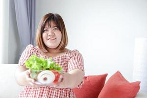 grasa asiático mujer llevar un taza de ensalada verduras a comer a perder peso y hacer ellos saludable. el concepto de comida a reducir barriga grasa sin enfermedad. con Copiar espacio. foto