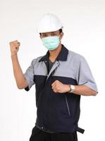 Asian engineer wearing a white safety helmet And wear a mask Act to raise your hands strong against virus and dust PM 2.5. Concept of industrial workers. White background photo