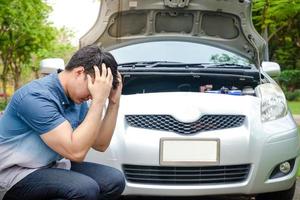 Stressful Asian men raise their hands to hold their heads The car engine crashed while traveling, parked on the roadside waiting for help. Concept of car insurance photo