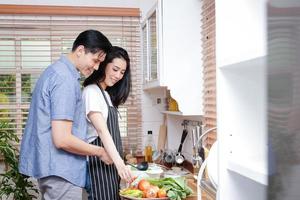 Asian couples cook together in the kitchen at home. They are happy. Concept of family, cooking, livelihoods during COVID-19, social distances. Copy space photo