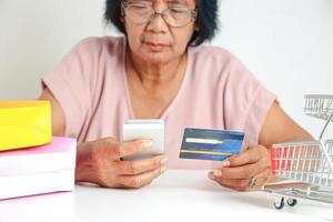 An elderly Asian woman holding a simulated credit card is not the real thing. Shopping online. Senior community concept photo