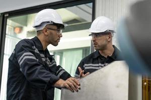 dos diverso profesional pesado industria ingenieros vistiendo la seguridad uniforme y difícil sombreros trabajando industria y Ingenieria personas tecnología concepto . foto