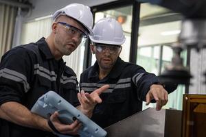 Two Diverse Professional Heavy Industry Engineers Wearing Safety Uniform and Hard Hats Working Industry and engineering people technology concept . photo