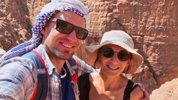 Caucasian couple tourist on viewpoint in Petra ancient city over Treasury or Al-khazneh take smartphone photo together. Jordan, one of seven wonders. UNESCO World Heritage site. video