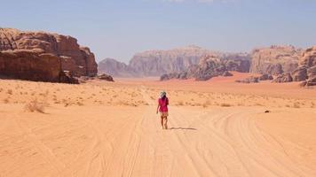 jong Kaukasisch vrouw controleren mobiele telefoon gedesoriënteerd verloren lezen kaart alleen in woestijn in extreem warmte. wadi rum woestijn wandeltocht en wandelen routes video