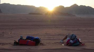 Jordan, 2022 - Young caucasian couple lay relax on sand together hold hand in love watch sunset in desert outdoors in wadi rum outdoors in Jordan. Travel explore togetherness in muslim country