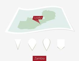 curvo papel mapa de Zambia con capital lusaka en gris antecedentes. cuatro diferente mapa alfiler colocar. vector