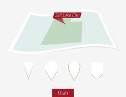 Curved paper map of Utah state with capital Salt Lake City on Gray Background. Four different Map pin set. vector