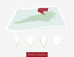 Curved paper map of North Carolina state with capital Raleigh on Gray Background. Four different Map pin set. vector