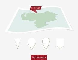 Curved paper map of Venezuela with capital Caracas on Gray Background. Four different Map pin set. vector