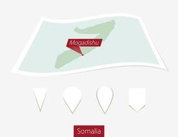 Curved paper map of Somalia with capital Mogadishu on Gray Background. Four different Map pin set. vector