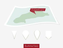 curvo papel mapa de burkina faso con capital ouagadougou en gris antecedentes. cuatro diferente mapa alfiler colocar. vector