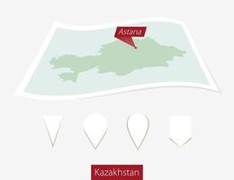 Curved paper map of Kazakhstan with capital Astana on Gray Background. Four different Map pin set. vector