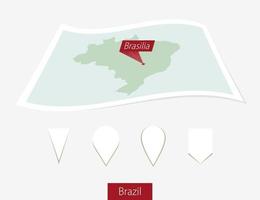 Curved paper map of Brazil with capital Brasilia on Gray Background. Four different Map pin set. vector