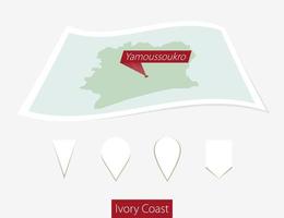 Curved paper map of Ivory Coast with capital Yamoussoukro on Gray Background. Four different Map pin set. vector