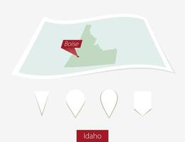 Curved paper map of Idaho state with capital Boise on Gray Background. Four different Map pin set. vector