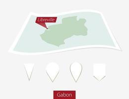 curvo papel mapa de Gabón con capital Libreville en gris antecedentes. cuatro diferente mapa alfiler colocar. vector