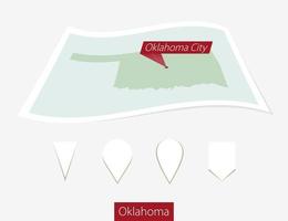 Curved paper map of Oklahoma state with capital Oklahoma City on Gray Background. Four different Map pin set. vector