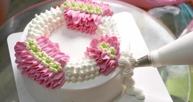 Close-up top view The chef is squeezing the cream into a flower shape on the top of the cake. video